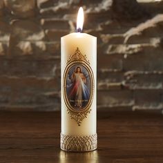 a lit candle with an image of the virgin mary on it