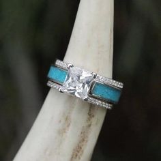 a white gold ring with blue stones and diamonds on it, sitting on a branch