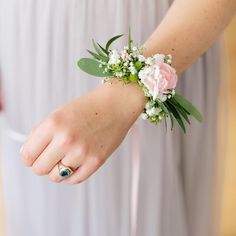 a woman wearing a ring and bracelet with flowers on her wrist is holding something in her hand