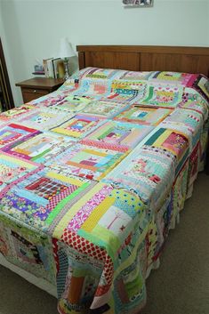 a bed with a multicolored quilt on it's headboard and foot board