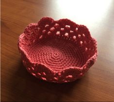 a pink crocheted bowl sitting on top of a wooden table