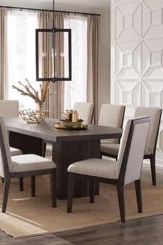 a dining room table with beige chairs and a chandelier hanging from the ceiling