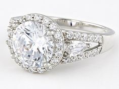 a white gold ring with an oval cut diamond surrounded by smaller round diamonds and pave set shoulders