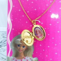 a barbie doll necklace with a photo on it and a gold plated locke attached to the chain