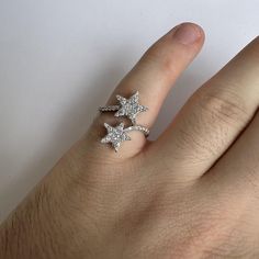 a person's hand wearing a ring with three stars on the middle of it