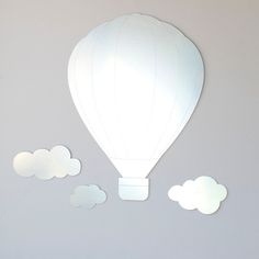 a white hot air balloon floating in the sky with clouds around it on a gray background