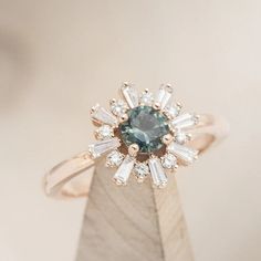 a blue diamond ring sitting on top of a wooden block