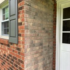 the corner of a brick building with a white door and window