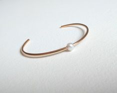 Simple, timeless, clean and beautiful! This pearl cuff bracelet is simply gorgeous. Each pearl is hand-drilled and sits very pretty along the top of this minimalist design. You can choose from 14kt gold fill, 14kt rose gold fill or sterling silver. Each genuine pearl is approximately 6mm in diameter. You can select from small, medium and large according to your wrist size. Your bracelet will arrive in a gift box with bow. Classic White Cuff Bracelet For Wedding, Minimalist White Cuff Bracelet As A Gift, Classic Adjustable Cuff Bracelet For Wedding, Minimalist White Cuff Bracelet As Gift, Dainty Bangle Cuff Bracelet For Anniversary, Dainty Anniversary Cuff Bracelet Bangle, Classic Cuff Bracelets For Wedding, Classic Cuff Wedding Jewelry, Classic White Bangle For Wedding