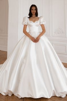 a woman in a white wedding dress posing for the camera with her hands on her hips