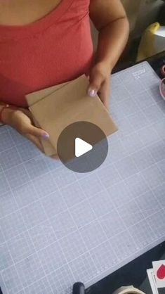 a woman is cutting up a piece of paper with scissors and tape on it while holding a box