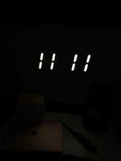 a laptop computer sitting on top of a desk next to a clock in the dark