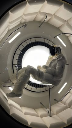 a person sitting on a chair in a room with white walls and stairs, looking up at the ceiling