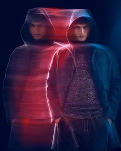 two young men standing next to each other in front of a red and blue light