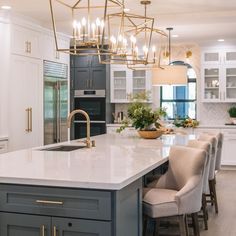 a large kitchen with an island and lots of chairs around the counter top, surrounded by white cabinets