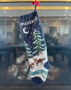 a stocking hanging from the ceiling in front of a window with christmas decorations on it