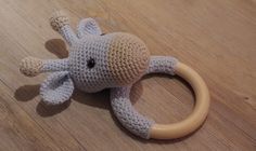 a crocheted elephant toy is on the floor with a wooden ring around it