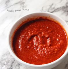 a white bowl filled with red sauce on top of a marble counter