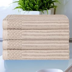 three folded towels sitting on top of a table next to a potted green plant