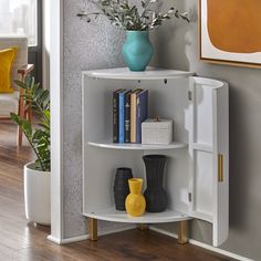 a corner shelf with books and vases on it next to a wall mounted painting