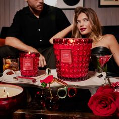 a man and woman sitting next to each other at a table with candles on it