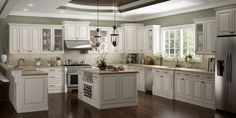 a large kitchen with white cabinets and wood floors