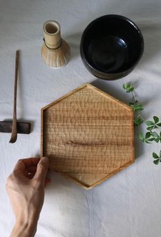 a person holding a wooden cutting board next to other items