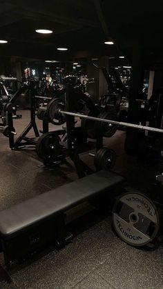 a gym with rows of weight machines and barbells in the background at night