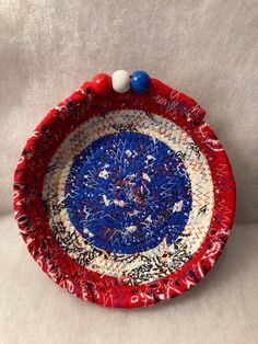 a red, white and blue bowl with beads on it