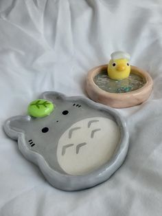 two rubber ducks in a bowl on a bed