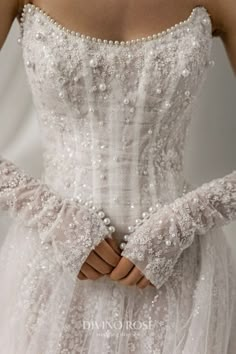 a woman in a white wedding dress with pearls on her arm and hands wrapped around the waist