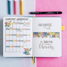 an open planner with colorful flowers on it next to markers, pens and pencils