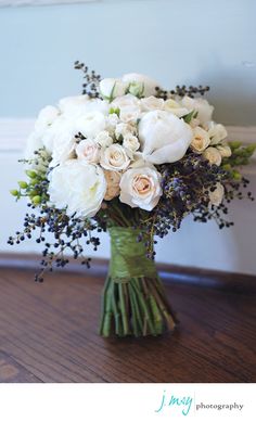 a bouquet of white roses and lavenders in a vase next to a man's suit