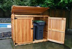 a wooden storage shed with two trash cans in it