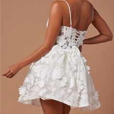 the back of a woman's white dress with flowers and laces on it