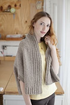 a woman standing in front of a kitchen counter wearing a sweater and leggings