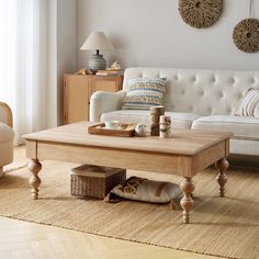 a living room with a couch, coffee table and pillows on the floor in front of a window