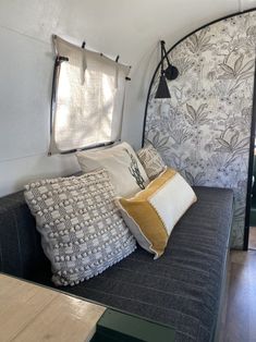 a couch with several pillows on it in front of a wallpapered headboard