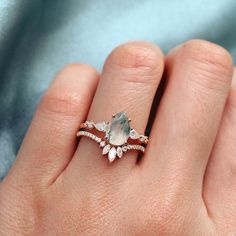 a woman's hand with a ring on it that has a pear shaped stone in the middle