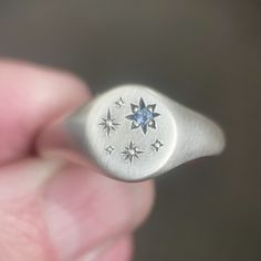 This blue Montana sapphire star signet ring in sterling silver has hand engraved stars which will vary slightly with each ring. If you'd like this design customized for you or need a rush order, contact me. DETAILS - hand engraved star/bead setting - 2 mm medium light blue Montana sapphire - ring measures 9 mm on top, tapers to 3 mm in back. - soft satin and oxidized finish emphasizes star details - hand engraved star pattern will vary slightly with each ring - made to order within 3-5 days IMPORTANT: Please be aware that delivery times are estimates and USPS may experience delays. Please be sure to look at estimated ship dates on made to order items and contact me if you need your order to arrive by a specific date.   Follow me on Instagram (ebethscottdesigns) and Facebook (Elizabeth Scot Elizabeth Scott, Space Rings, Montana Sapphire Ring, Paper Ring, Signet Rings, Medieval Jewelry, Plastic Ring, Silver Signet Ring, Montana Sapphire