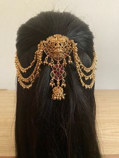 a woman's head wearing a gold and red hair piece with chains attached to it