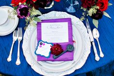 the table is set with purple and red napkins, silverware, and flowers