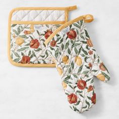 an oven mitt and pot holder with apples on them sitting next to each other