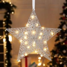 a white star shaped christmas ornament hanging from a string with lights on it