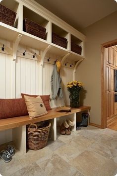 a wooden bench sitting next to a white wall with baskets on it's sides