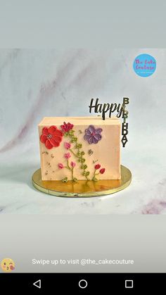 a birthday cake decorated with flowers and the words happy birthday on it's side