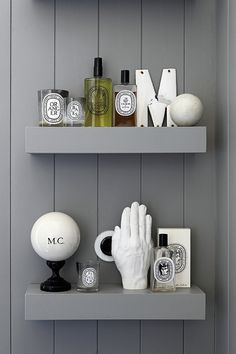 two shelves with bottles, soaps and other items on them in a gray room