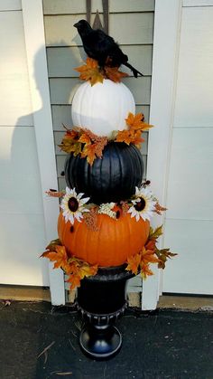 three pumpkins stacked on top of each other in front of a door with leaves