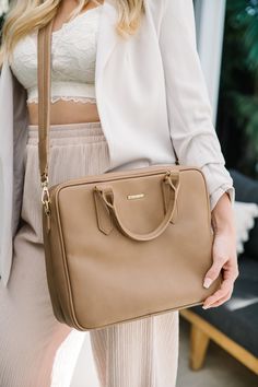 a woman holding a tan purse in her hand