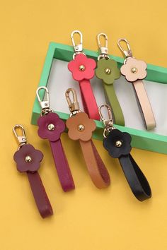 four keychains with flower charms on them sitting in front of a yellow background